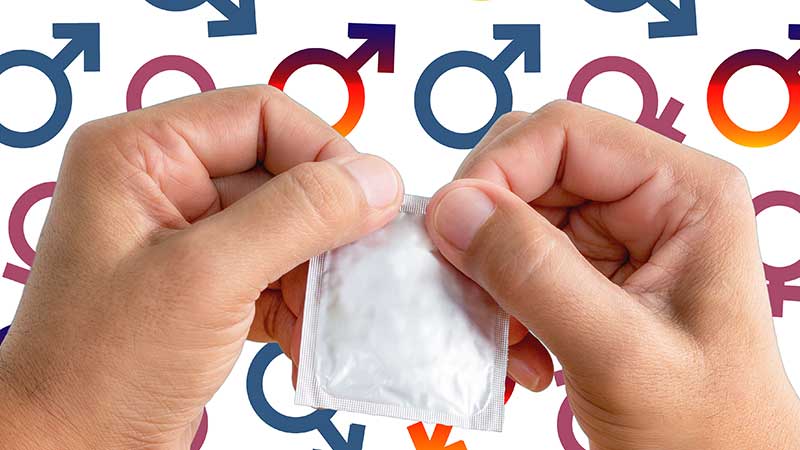 Mãos a abrir um preservativo com símbolos de masculino e feminino à volta